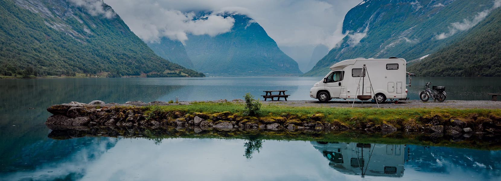 A motorhome parked beside a calm and picturesque Loch Lomand in Scotland