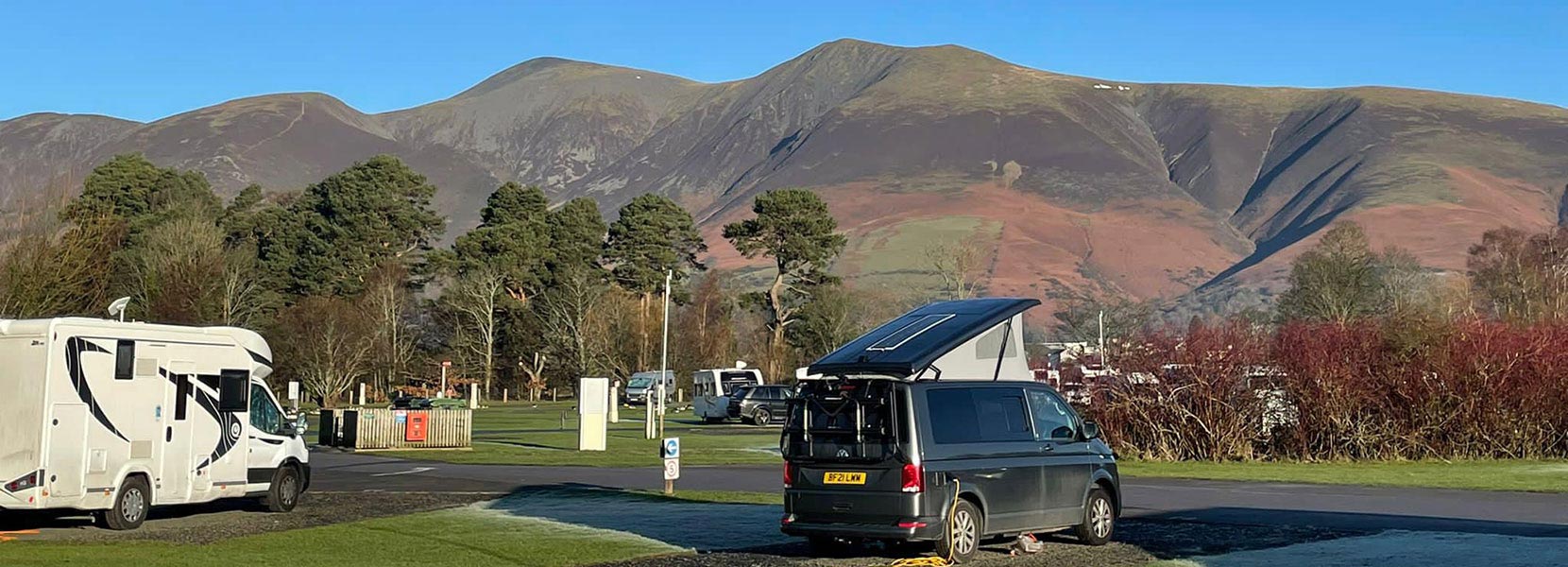 Motorhomes pitched at a campsites overlooking a picturesque view of the Scottish Highlands or Lake District